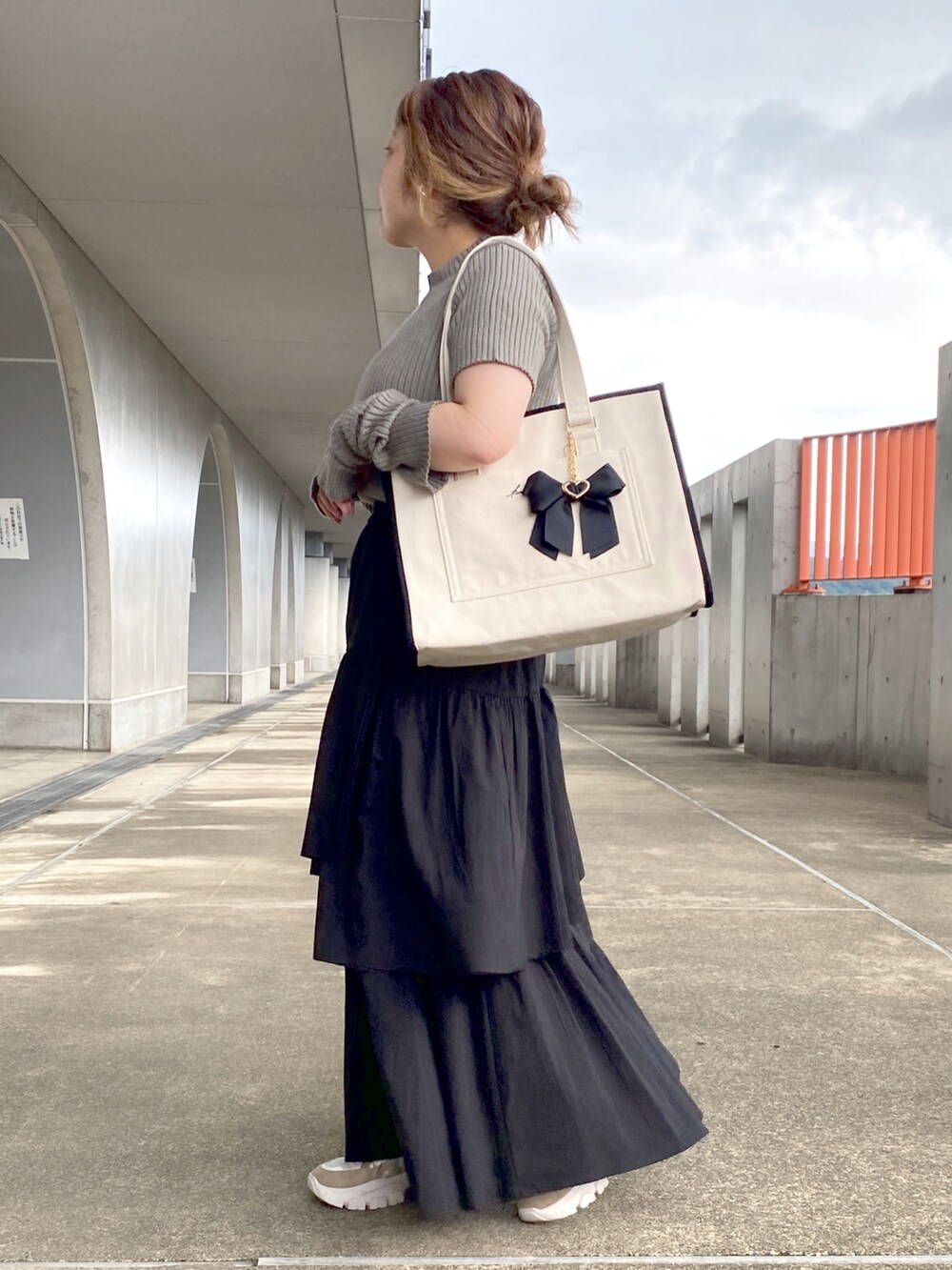 グリーン系のニット/セーター、ブラック系のトートバッグ、ブラック系のスカートを着用したレディースの夏コーディネートの2枚目の写真