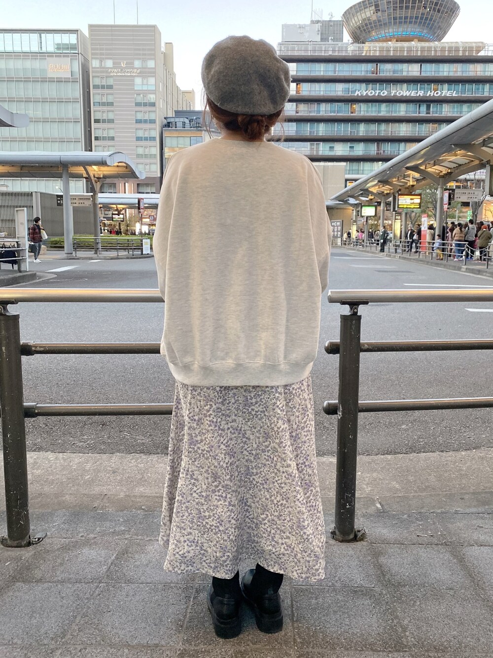 グレー系のスウェット、ブラウン系のトートバッグ、パープル系のワンピースを着用したレディースの秋コーディネートの3枚目の写真