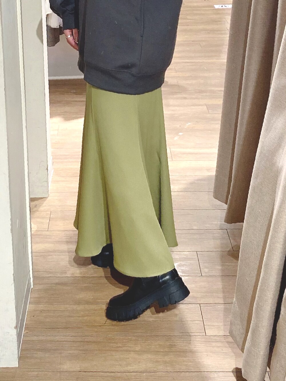 ブラック系のスウェット、グリーン系のスカート、ブラック系のブーツを着用したレディースの冬コーディネートの3枚目の写真