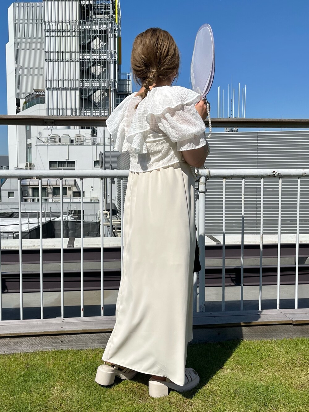 ホワイト系のワンピース、ブラック系のトートバッグ、ホワイト系のサンダルを着用したレディースの春コーディネートの2枚目の写真