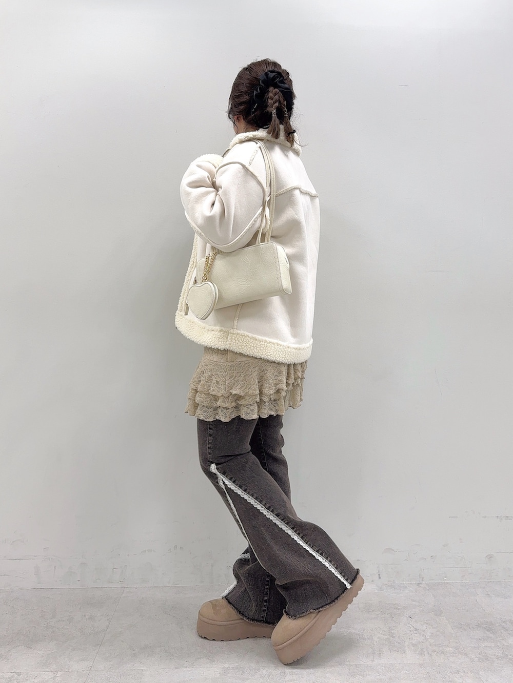 ホワイト系のブルゾン、ベージュ系のワンピース、ブラック系のデニムパンツを着用したレディースの秋コーディネートの2枚目の写真