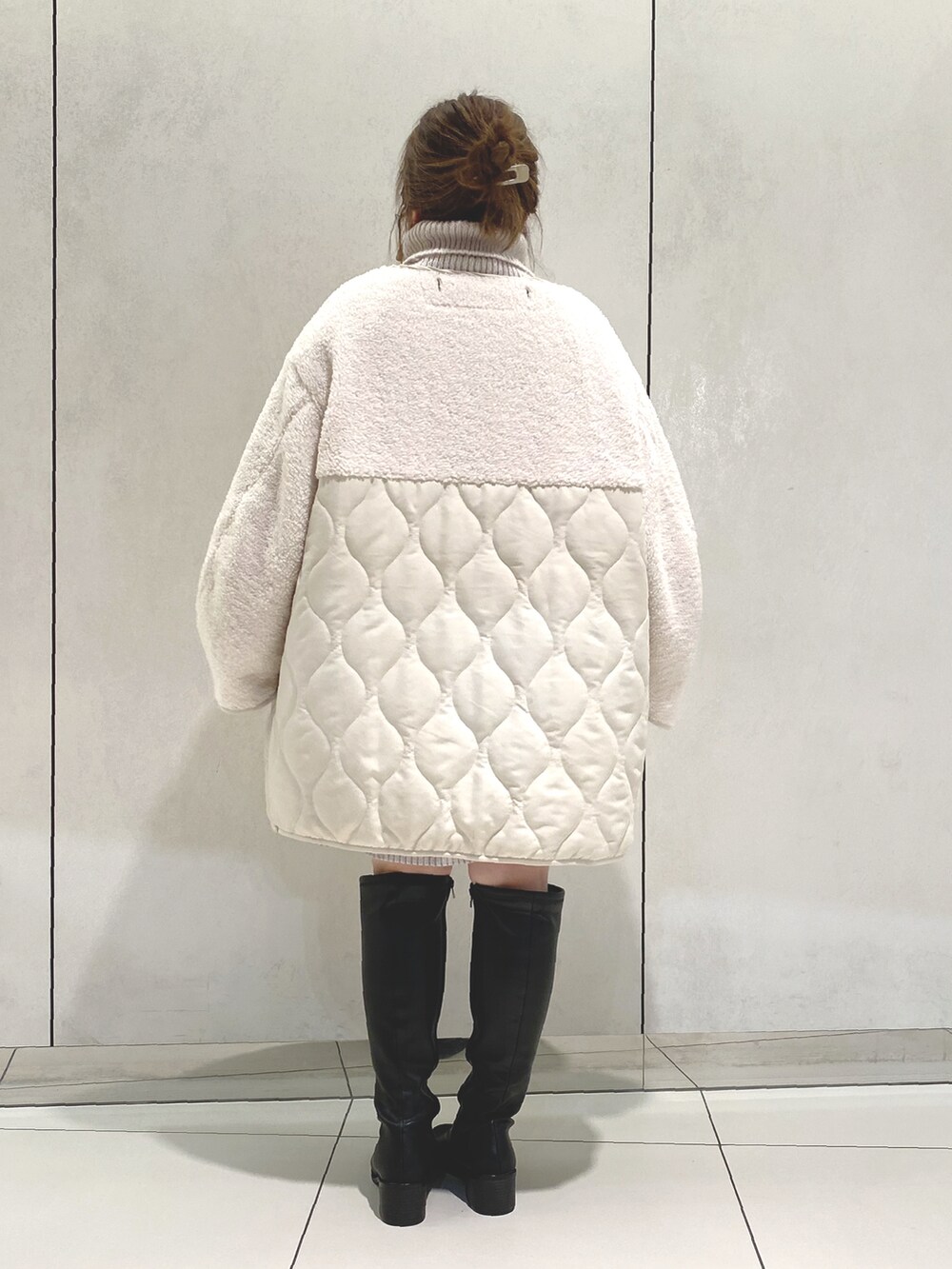 ホワイト系のノーカラーコート、グレー系のニット/セーター、ベージュ系のワンピースを着用したレディースの冬コーディネートの3枚目の写真