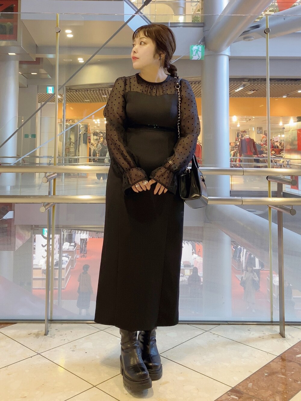 ブラック系のドレス、ブラック系のショルダーバッグ、ブラック系のブーツを着用したレディースの秋コーディネートの2枚目の写真