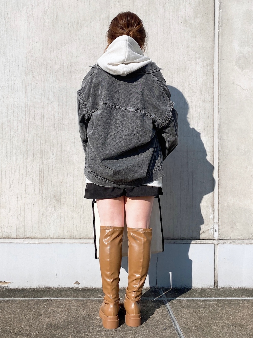 グレー系のパーカー、ブラック系のトートバッグ、イエロー系のブーツを着用したレディースの冬コーディネートの3枚目の写真