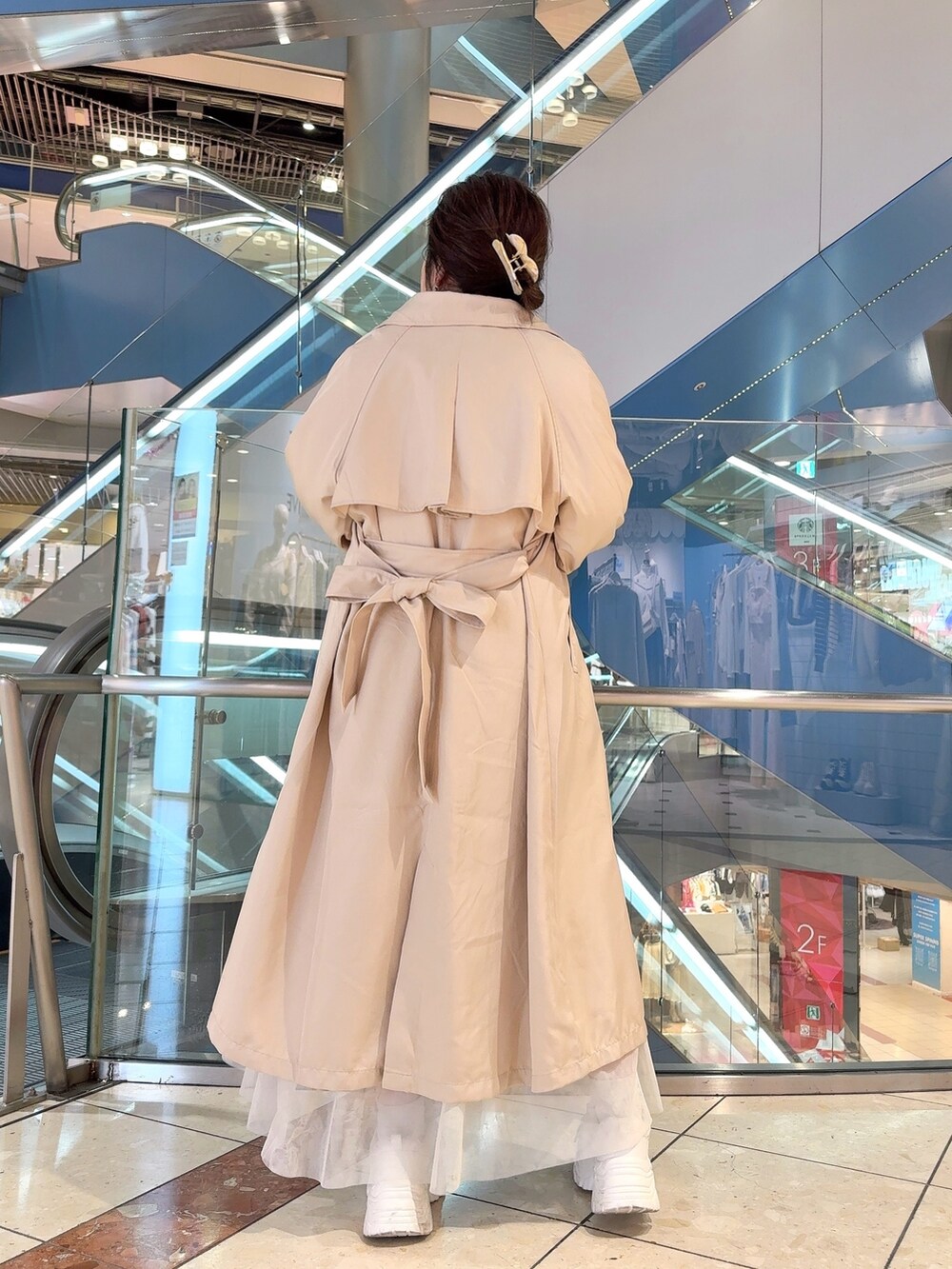 ベージュ系のトレンチコート、ホワイト系のワンピース、ホワイト系のショルダーバッグを着用したレディースの冬コーディネートの3枚目の写真