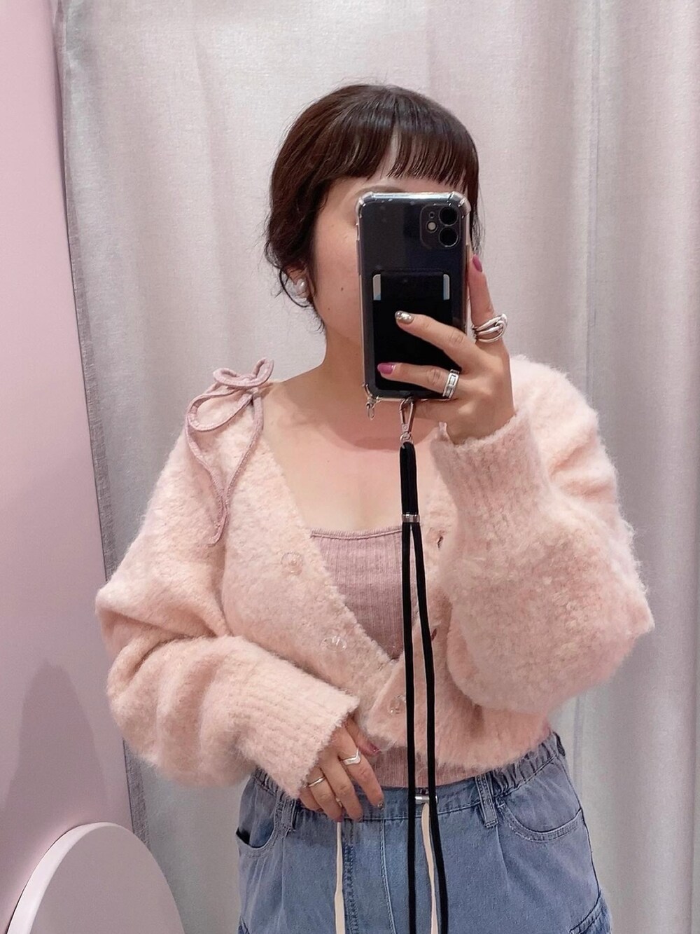 ピンク系のカーディガン/ボレロ、ピンク系のキャミソール、ブルー系のカーゴパンツを着用したレディースの秋コーディネートの2枚目の写真