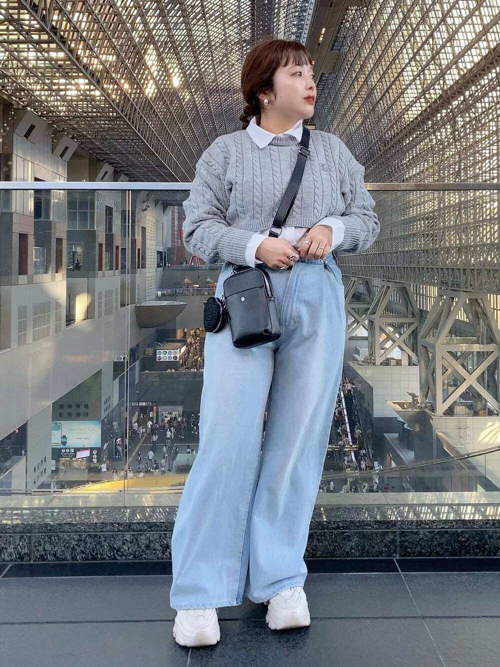 グレー系のニット/セーター、ブルー系のデニムパンツ、ブラック系のショルダーバッグを着用したレディースの夏コーディネートの2枚目の写真