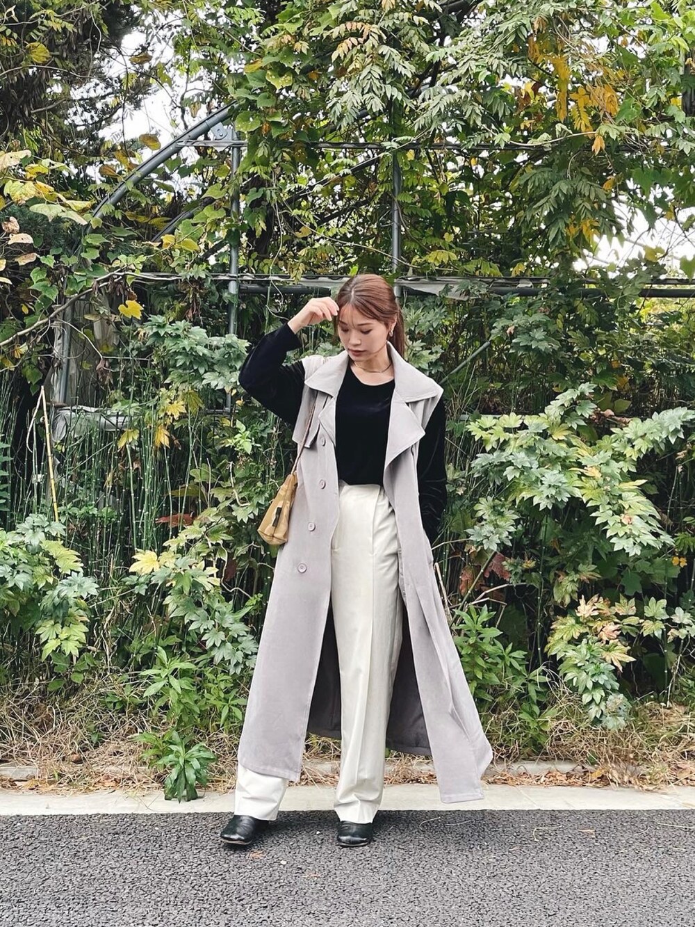 ブラック系のトップス、グレー系のトレンチコート、ホワイト系のその他パンツを着用したレディースの秋コーディネートの3枚目の写真