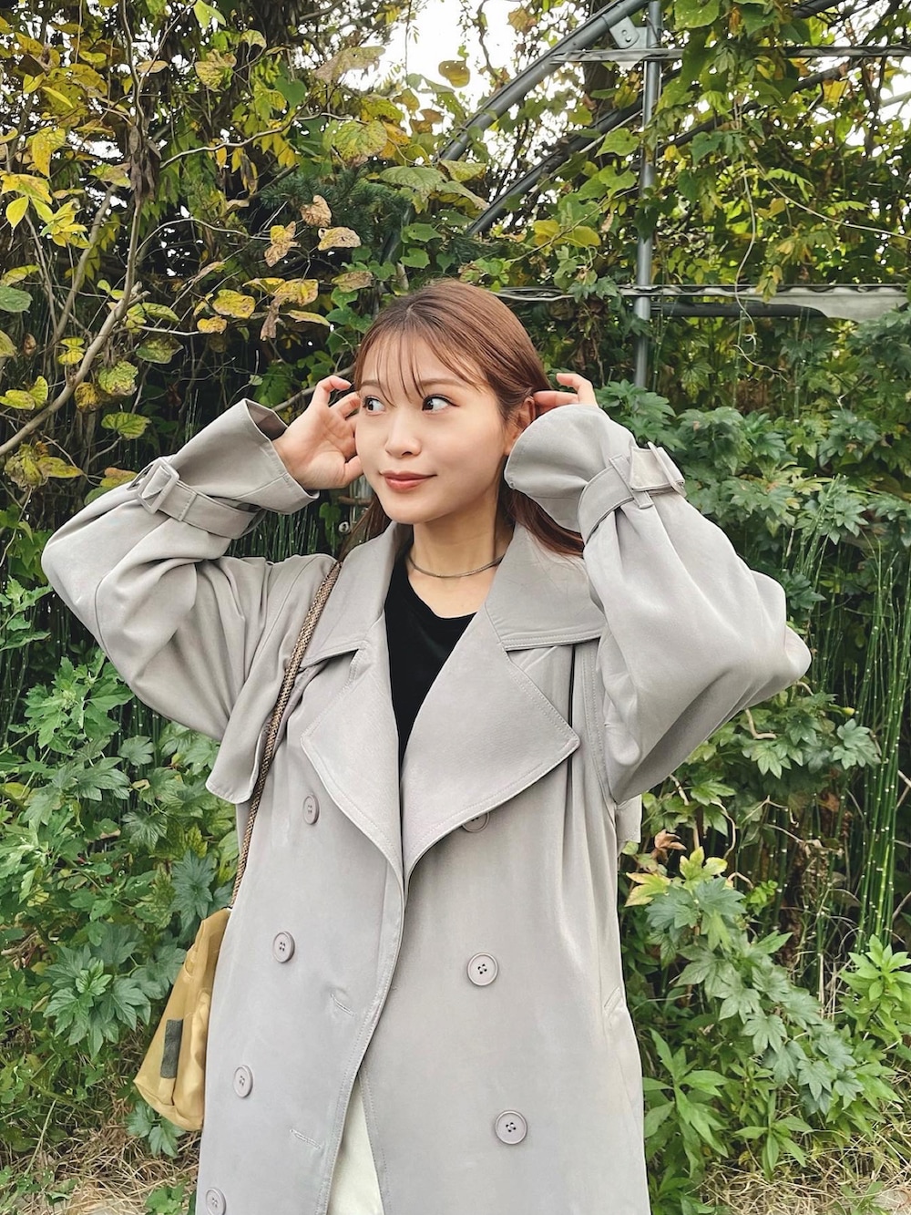 ブラック系のトップス、グレー系のトレンチコート、ホワイト系のその他パンツを着用したレディースの秋コーディネートの4枚目の写真