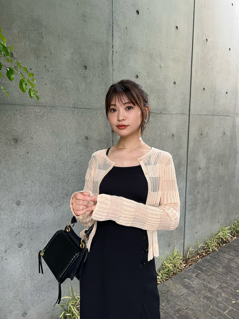 ブラック系のスカート、オレンジ系のカーディガン/ボレロ、ブラック系のショルダーバッグを着用したレディースの春コーディネートの2枚目の写真