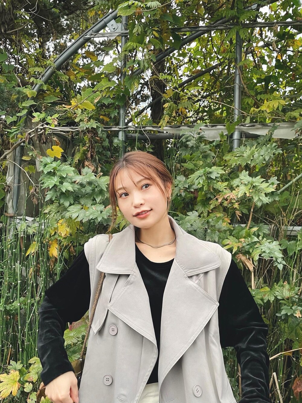 ブラック系のトップス、グレー系のトレンチコート、ホワイト系のその他パンツを着用したレディースの秋コーディネートの2枚目の写真