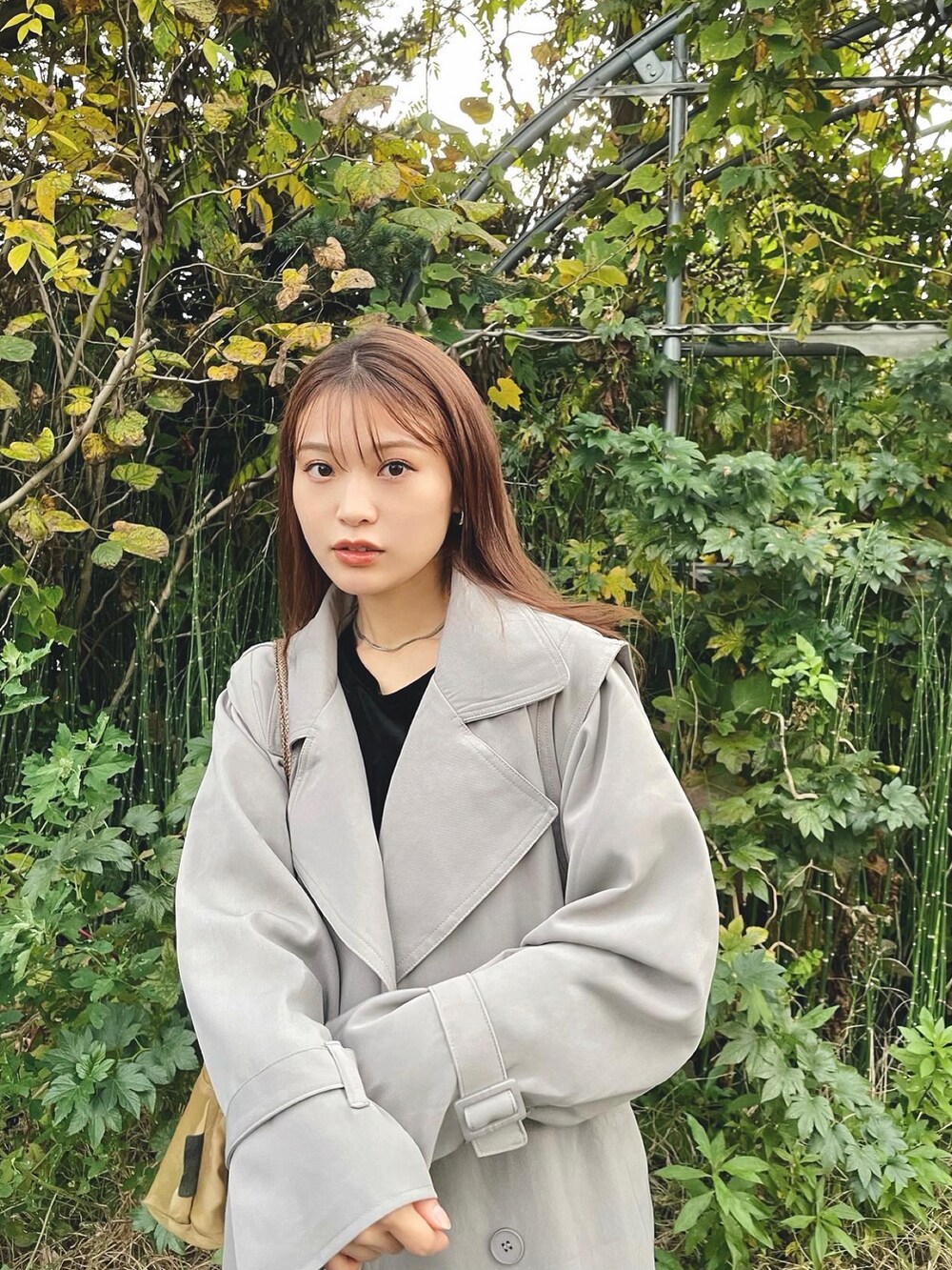 ブラック系のトップス、グレー系のトレンチコート、ホワイト系のその他パンツを着用したレディースの秋コーディネートの5枚目の写真