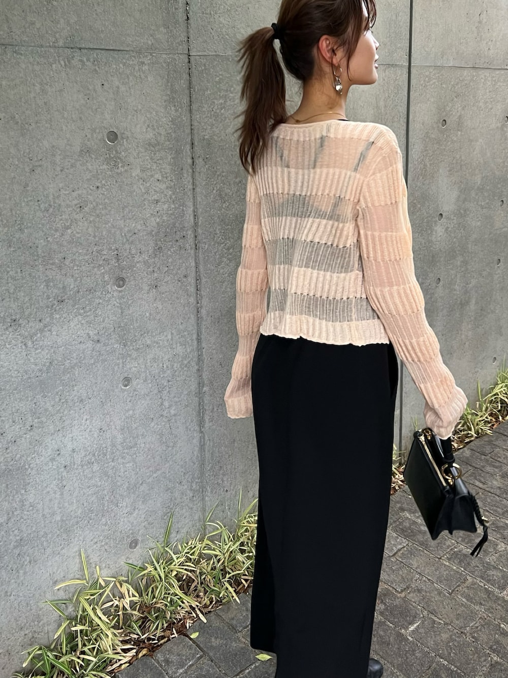 ブラック系のスカート、オレンジ系のカーディガン/ボレロ、ブラック系のショルダーバッグを着用したレディースの春コーディネートの3枚目の写真