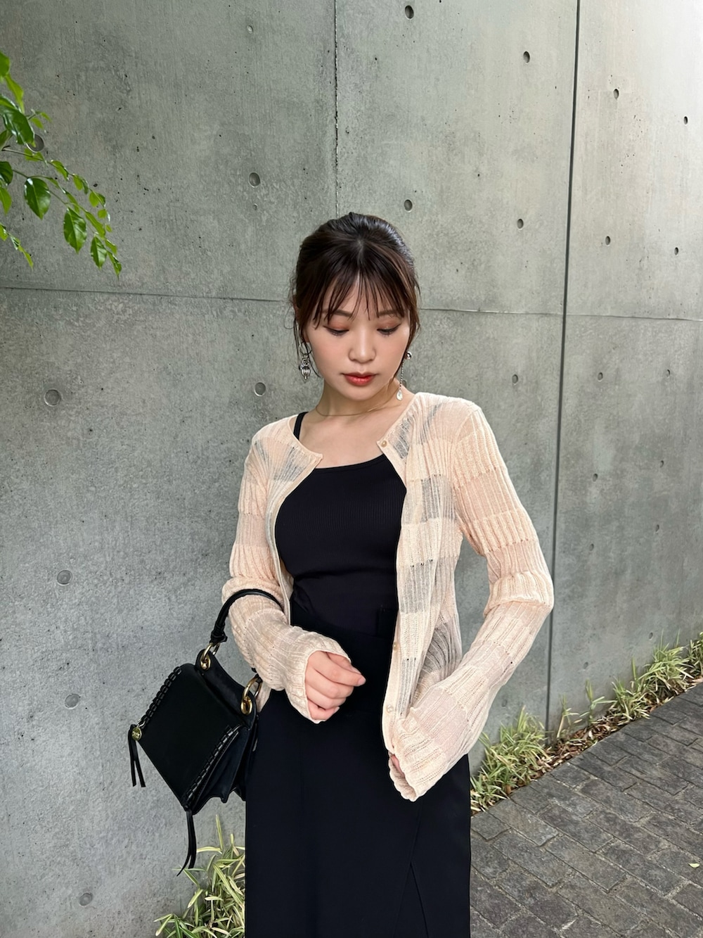 ブラック系のスカート、オレンジ系のカーディガン/ボレロ、ブラック系のショルダーバッグを着用したレディースの春コーディネートの4枚目の写真