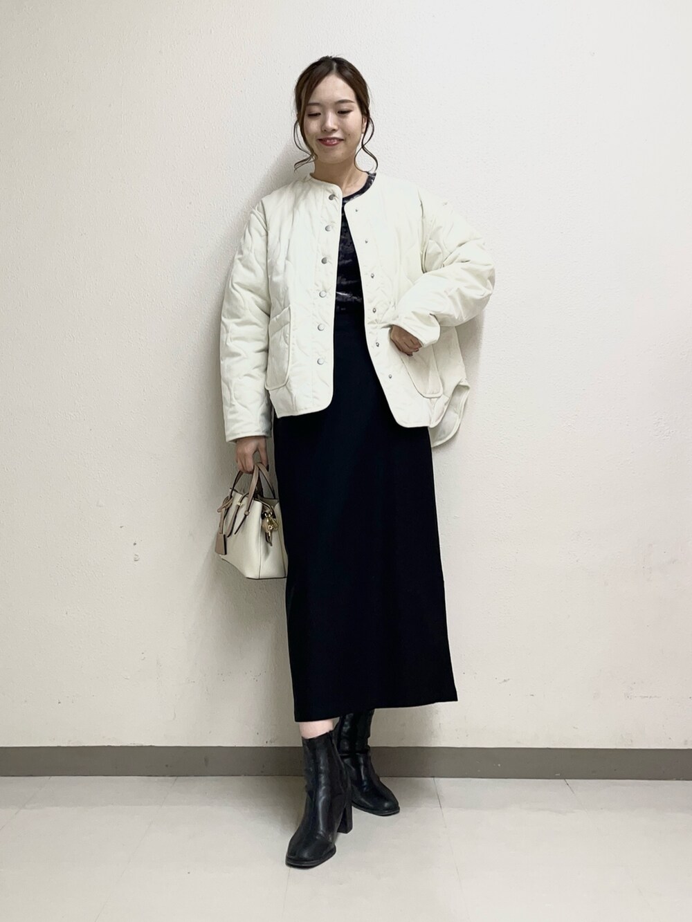 ベージュ系のスカート、ホワイト系のトートバッグ、ブラック系のブーツを着用したレディースの春コーディネートの3枚目の写真
