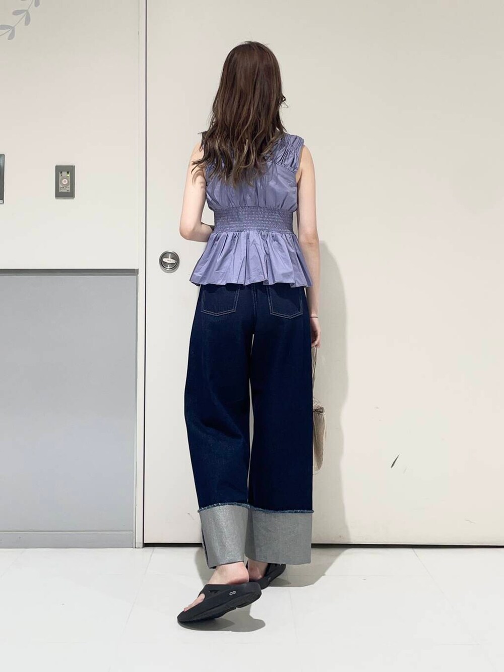 ホワイト系のキャミソール、ブラック系のサンダル、ゴールド系のハンドバッグを着用したレディースの夏コーディネートの2枚目の写真