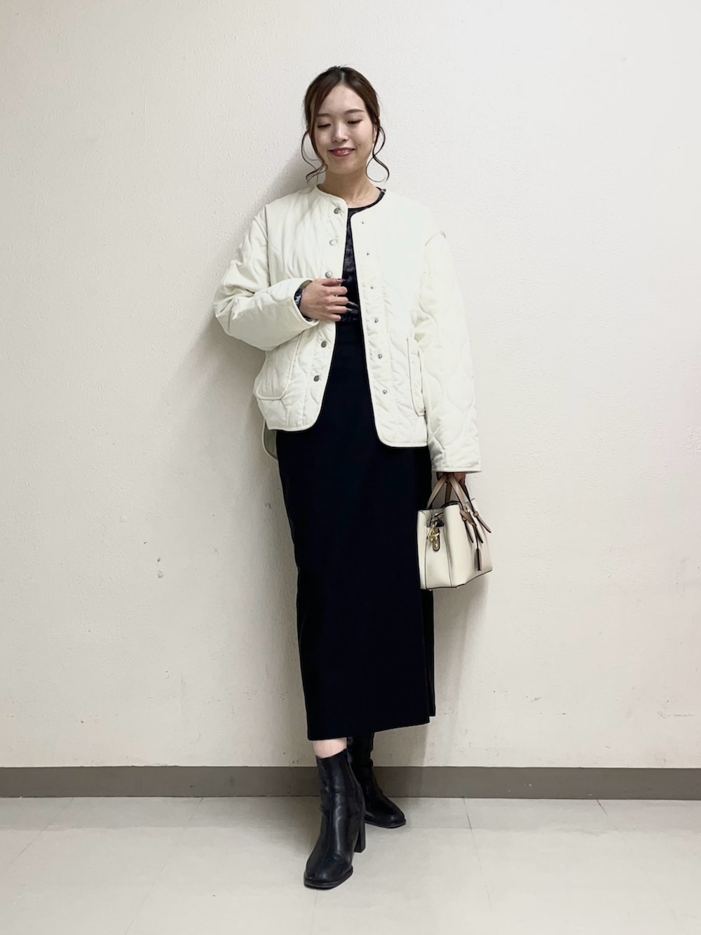 ベージュ系のスカート、ホワイト系のトートバッグ、ブラック系のブーツを着用したレディースの春コーディネートの2枚目の写真