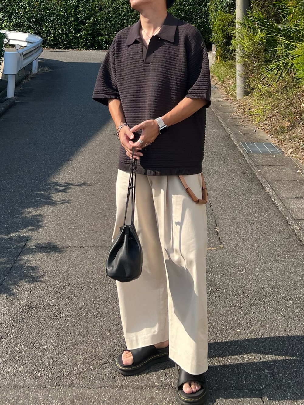 グレー系のポロシャツ、ブラック系のショルダーバッグ、ホワイト系のその他パンツを着用したメンズの夏コーディネートの3枚目の写真