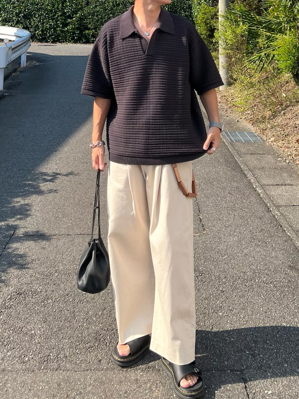 グレー系のポロシャツ、ブラック系のショルダーバッグ、ホワイト系のその他パンツを着用したメンズの夏コーディネートの2枚目の写真