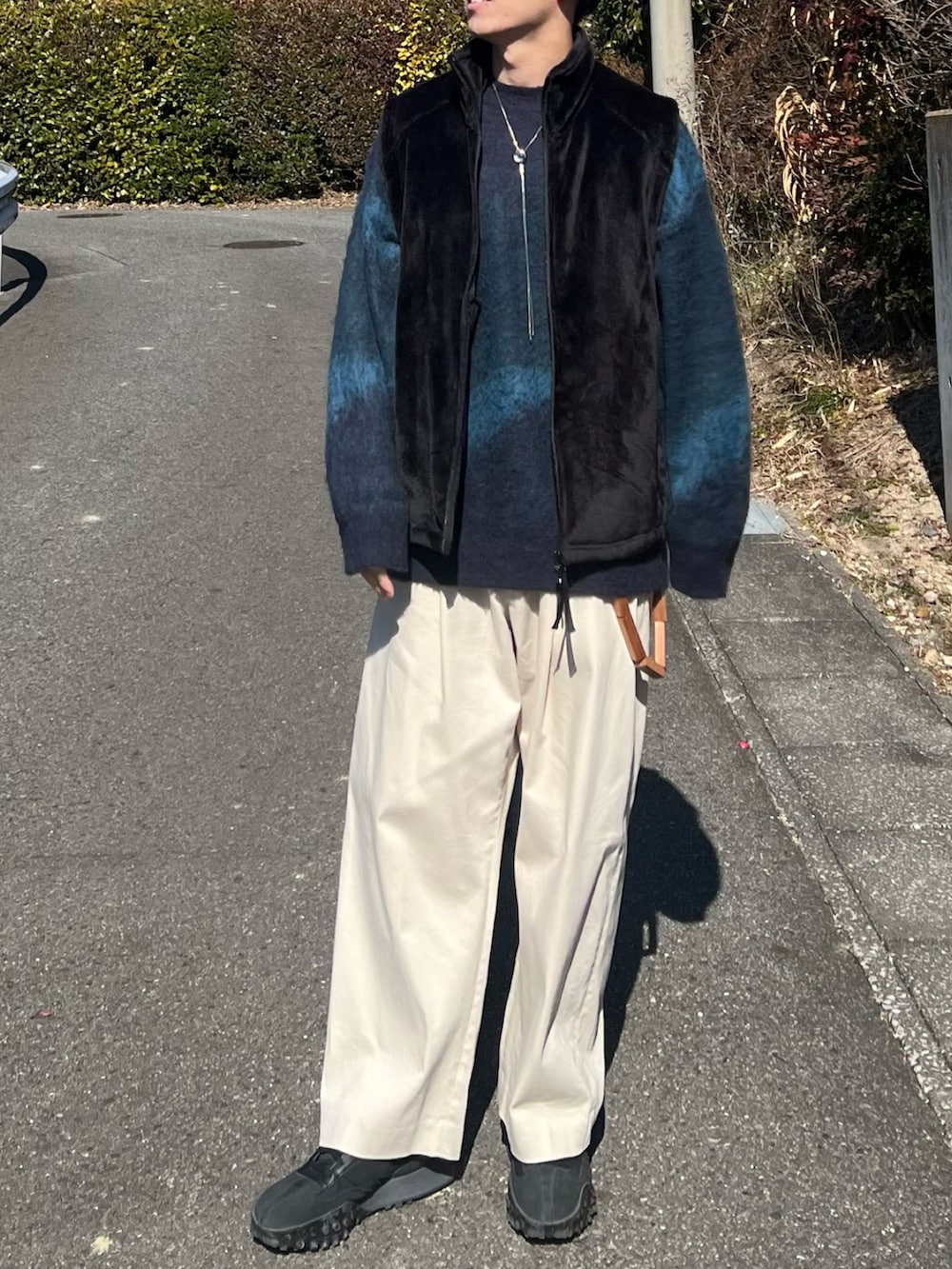 ブラック系のベスト、ホワイト系のその他パンツ、ブラック系のスニーカーを着用したメンズの冬コーディネートの2枚目の写真