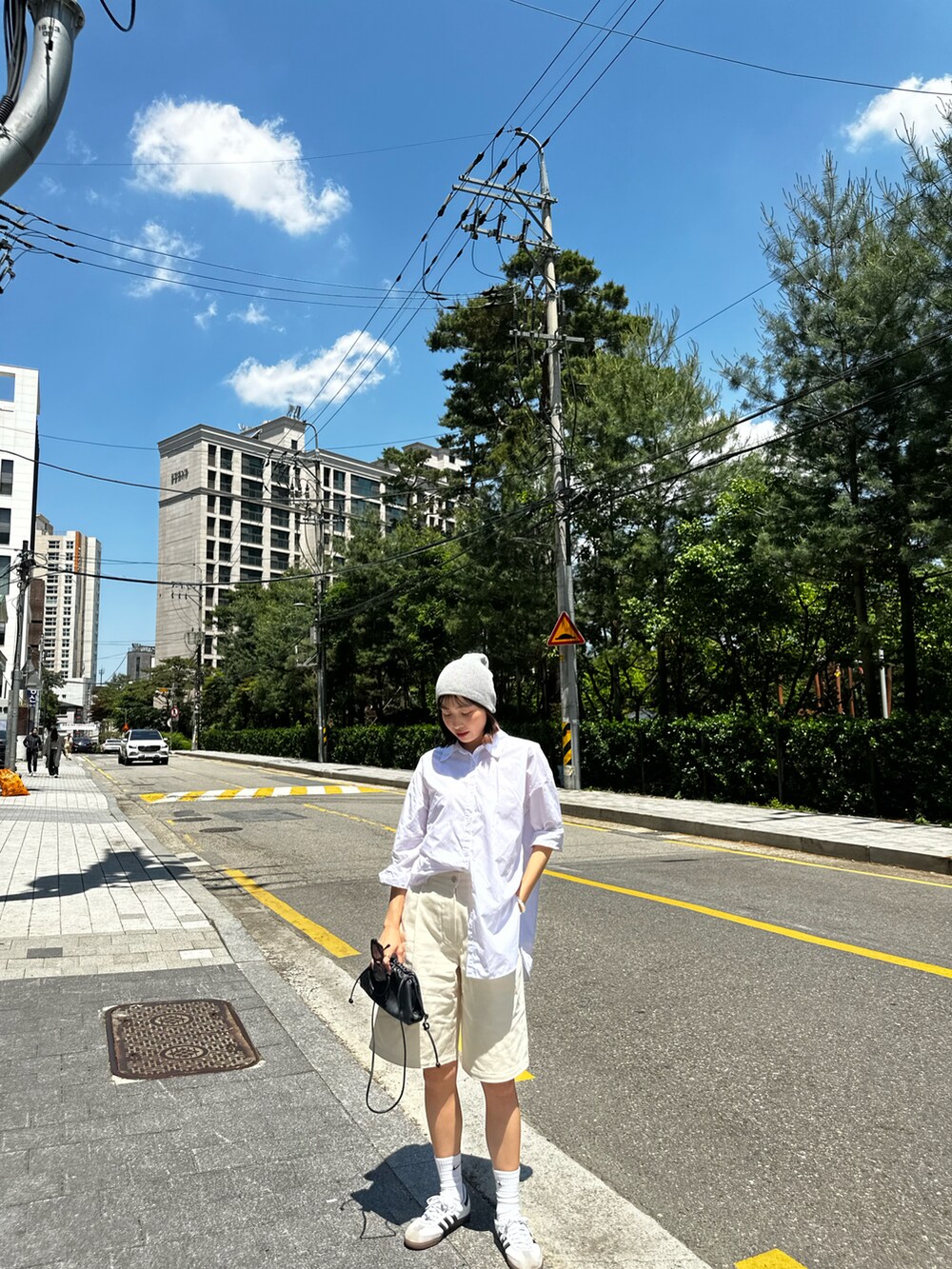 ホワイト系のシャツ/ブラウス、ブラック系のショルダーバッグ、ホワイト系のスニーカーを着用したレディースの夏コーディネートの4枚目の写真