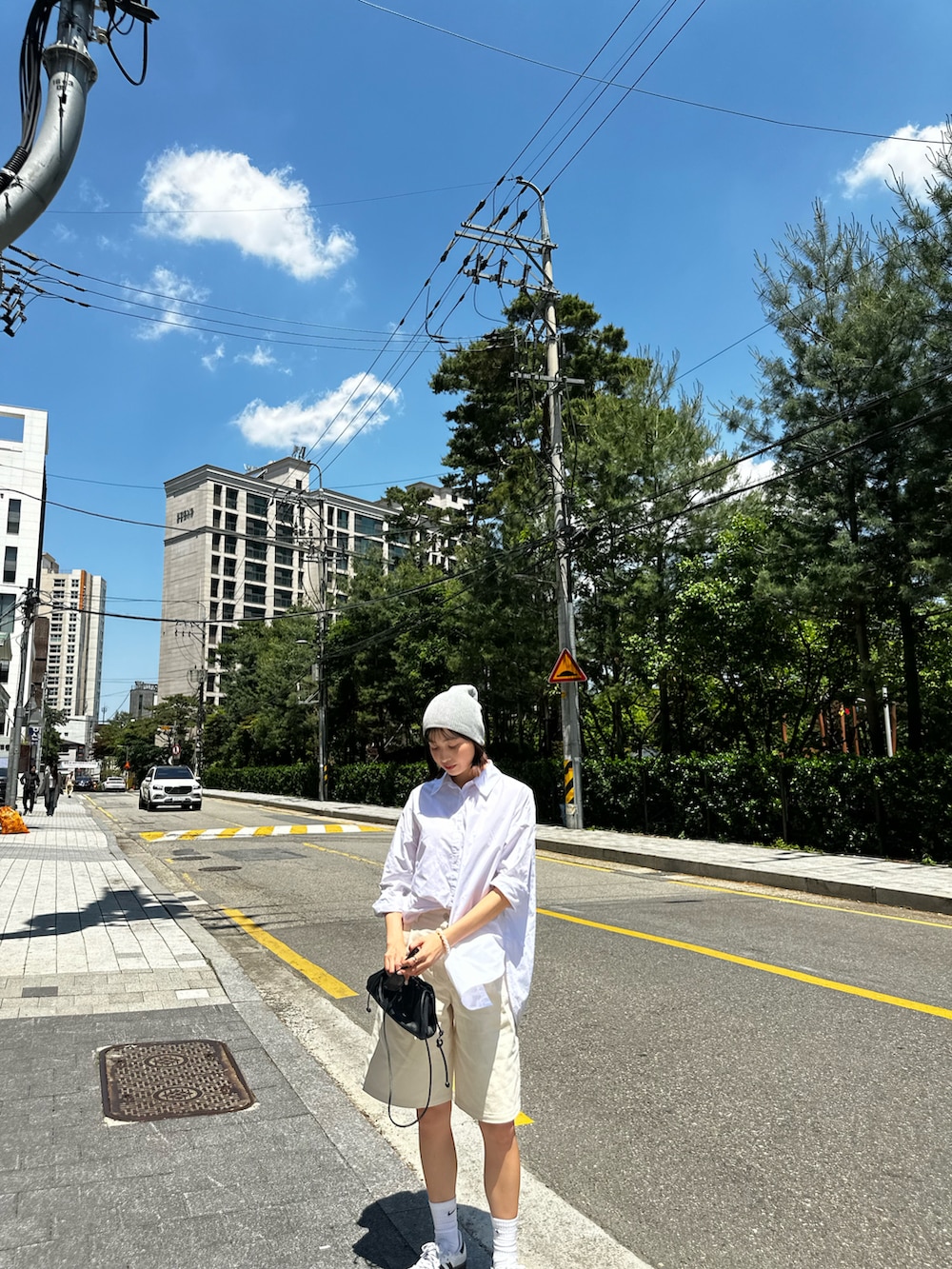 ホワイト系のシャツ/ブラウス、ブラック系のショルダーバッグ、ホワイト系のスニーカーを着用したレディースの夏コーディネートの3枚目の写真