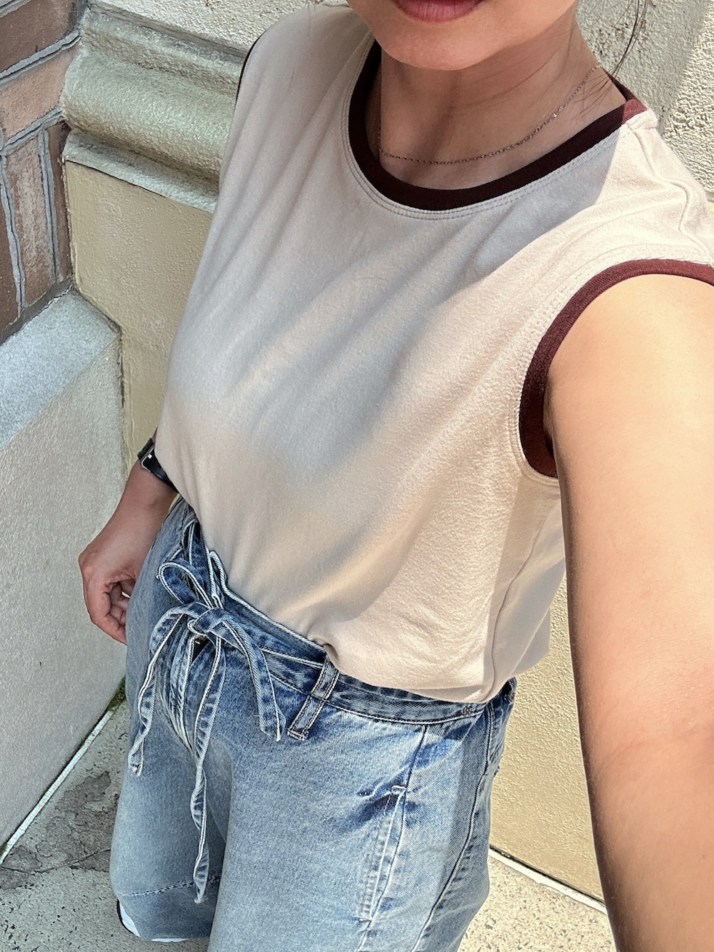 ベージュ系のタンクトップ、ブルー系のデニムパンツ、ホワイト系のスニーカーを着用したレディースの夏コーディネートの2枚目の写真