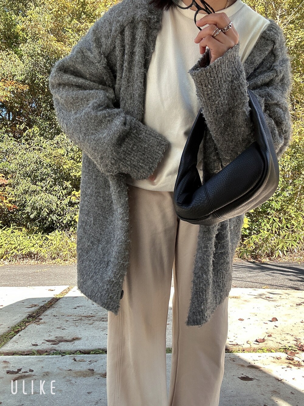 グレー系のカーディガン/ボレロ、ブラック系のハンドバッグ、ホワイト系のその他パンツを着用したレディースの秋コーディネートの2枚目の写真