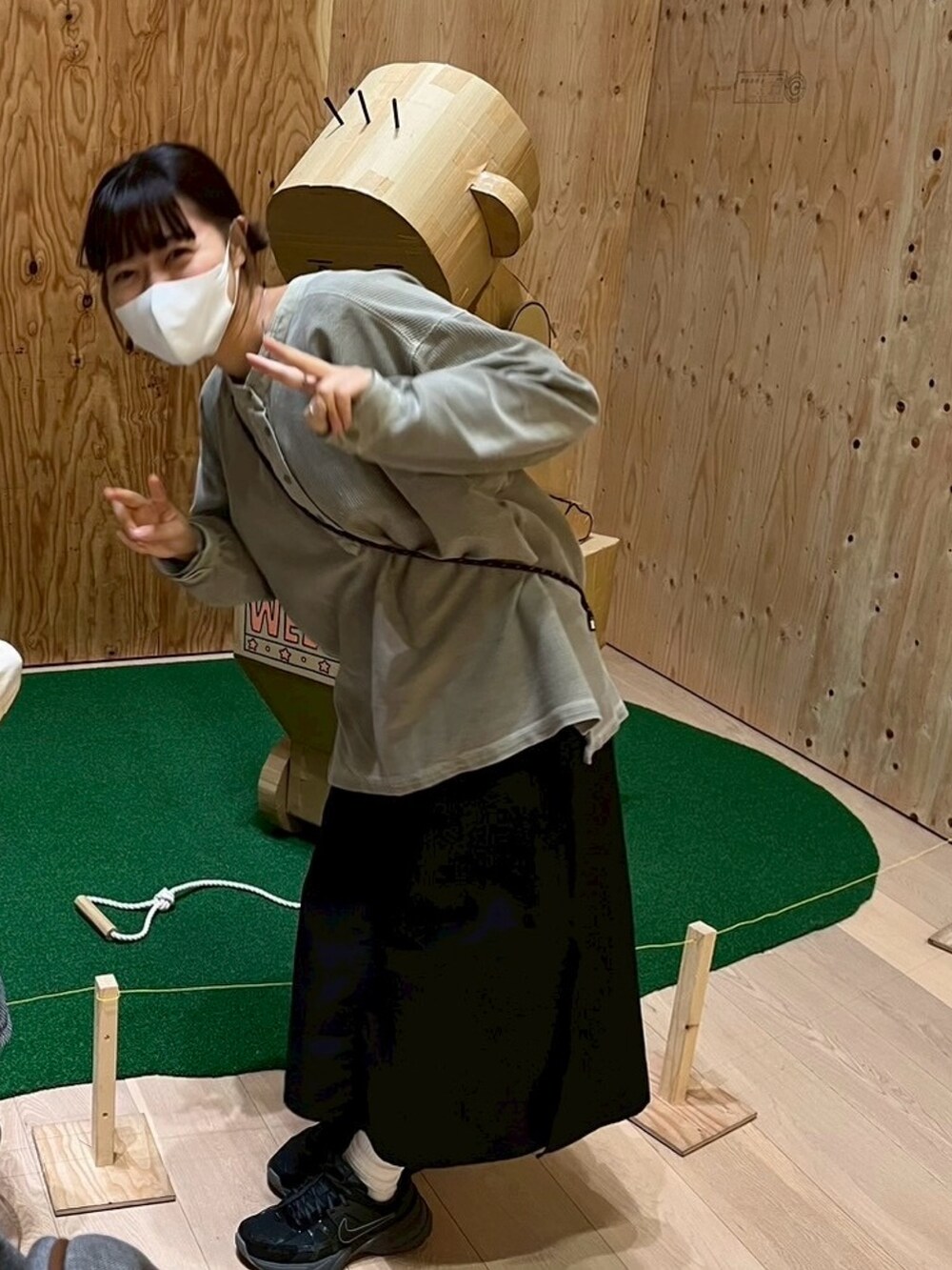 グリーン系のトップス、ブラック系のワンピース、ブラック系のスニーカーを着用したレディースの春コーディネートの2枚目の写真