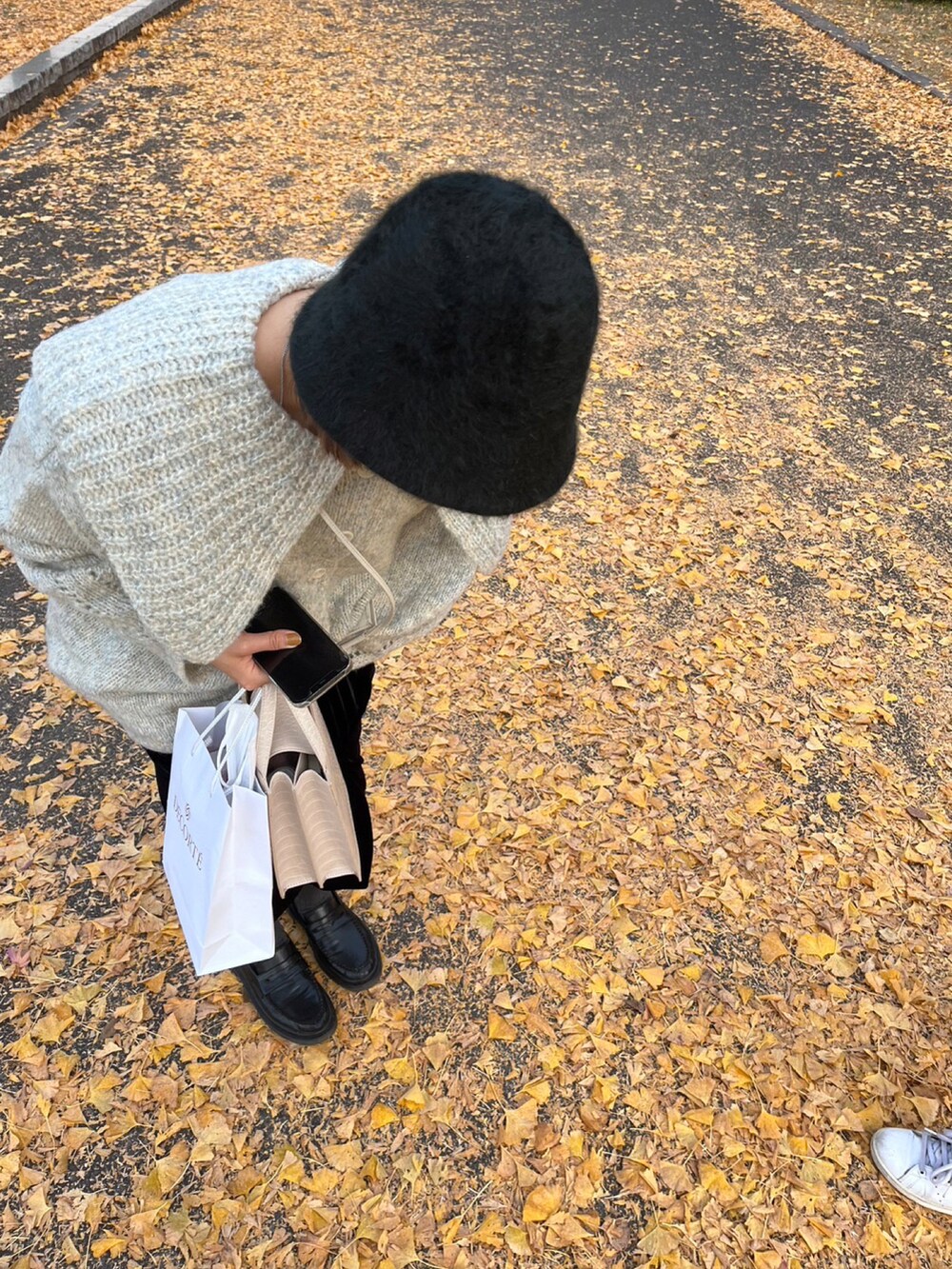 グレー系のニット/セーター、ブラック系のワンピース、ベージュ系のショルダーバッグを着用したレディースの秋コーディネートの2枚目の写真