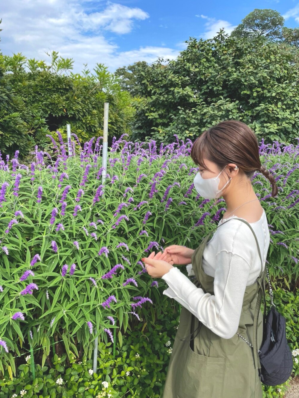 グリーン系のワンピース、ホワイト系のTシャツ/カットソー、ブラック系のスニーカーを着用したレディースの秋コーディネートの2枚目の写真