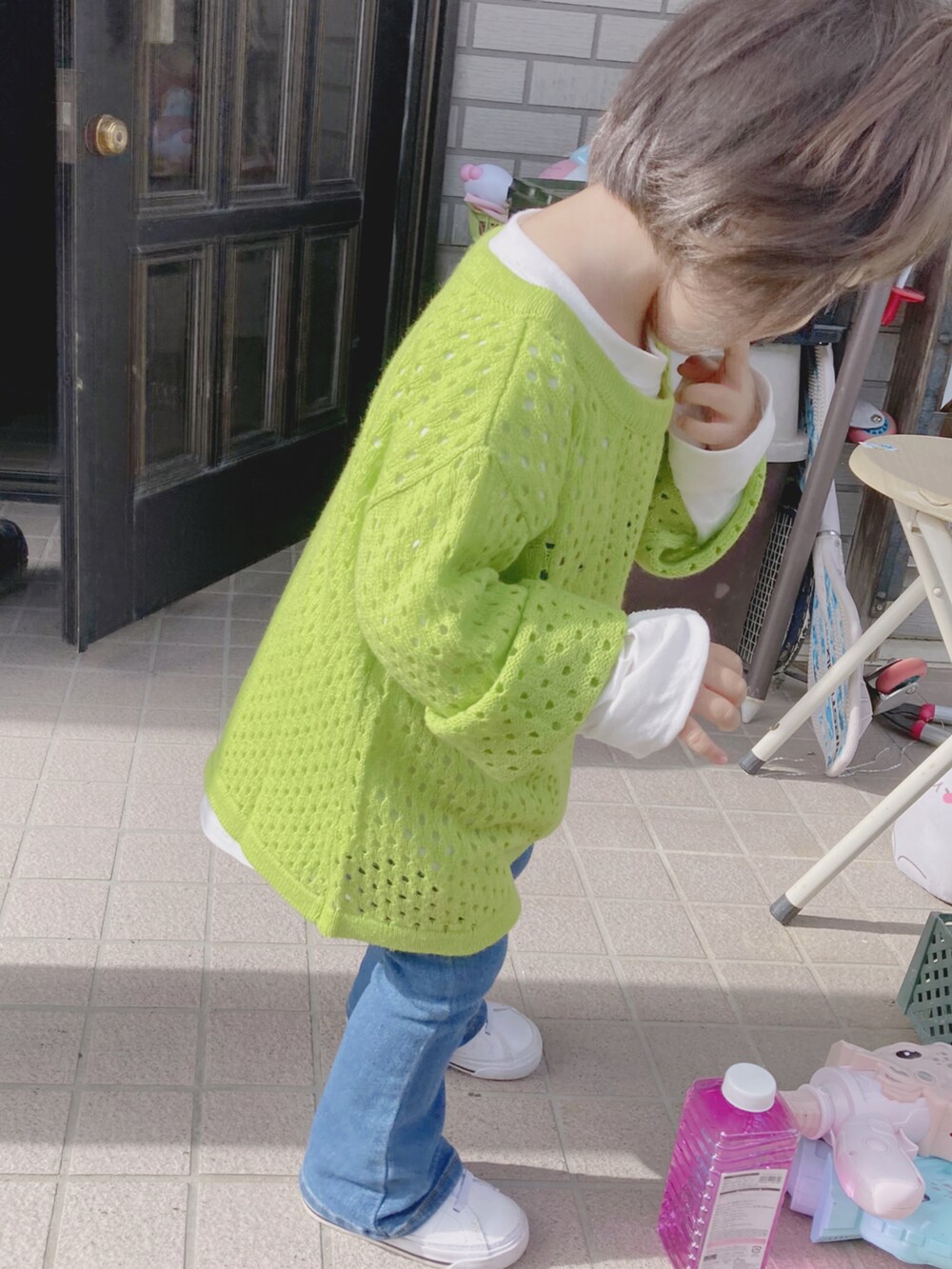 グリーン系のニット/セーター、ホワイト系のTシャツ/カットソー、ブルー系のデニムパンツを着用したキッズの秋コーディネートの2枚目の写真