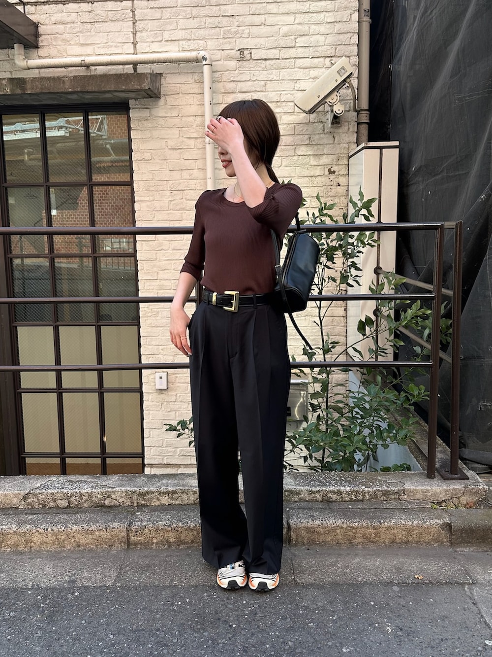 ブラウン系のニット/セーター、グレー系のスラックスを着用したレディースの春コーディネートの2枚目の写真