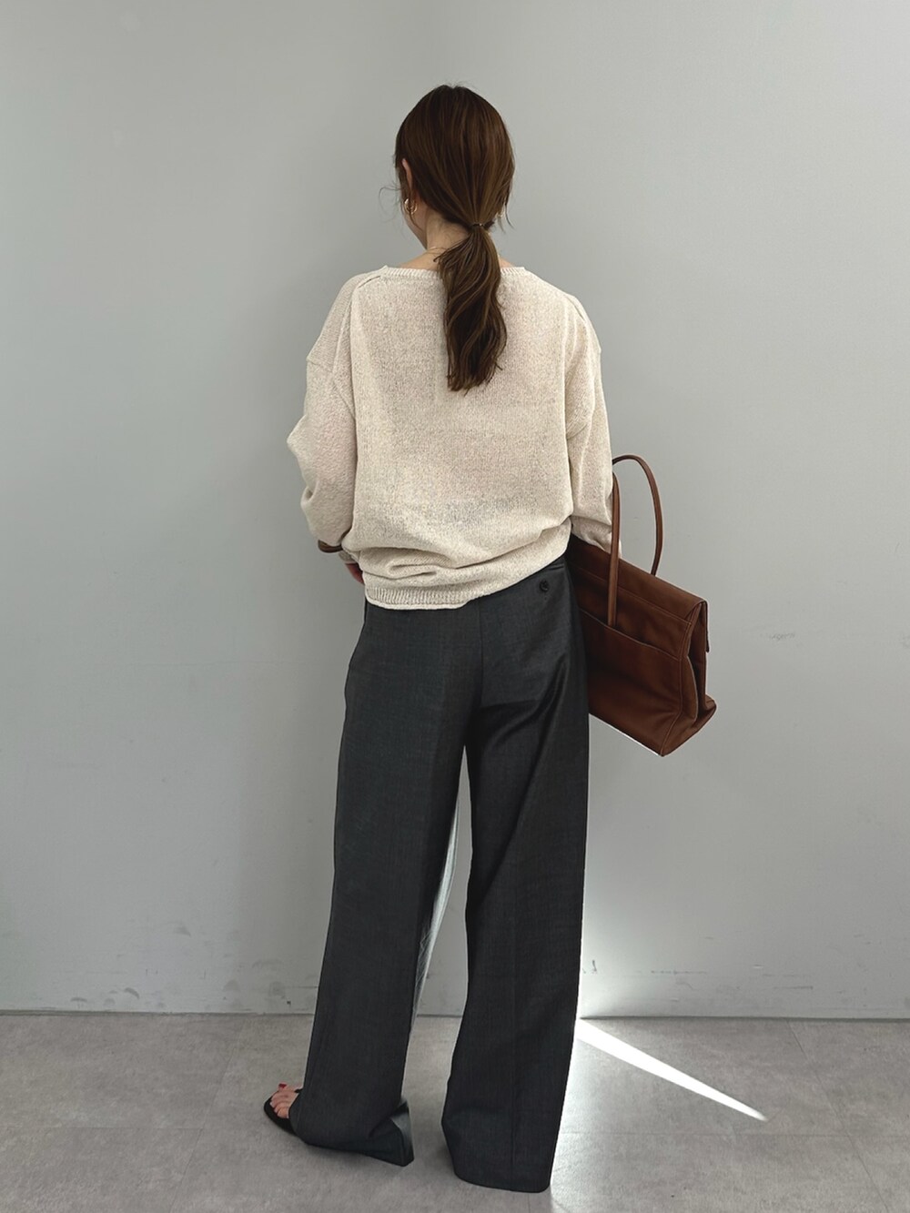 グレー系のスラックス、イエロー系のボストンバッグ、ベージュ系のニット/セーターを着用したレディースの春コーディネートの5枚目の写真