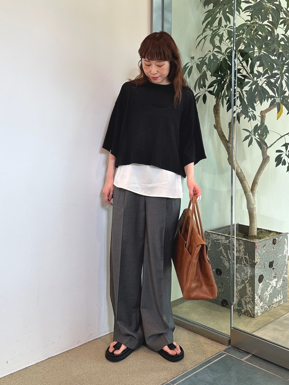 グレー系のスラックス、イエロー系のボストンバッグ、ホワイト系のシャツ/ブラウスを着用したレディースの夏コーディネートの3枚目の写真