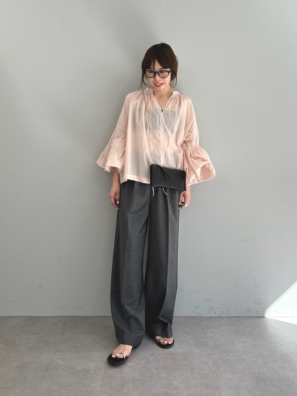 ピンク系のシャツ/ブラウス、グレー系のスラックス、ブラック系のショルダーバッグを着用したレディースの春コーディネートの3枚目の写真