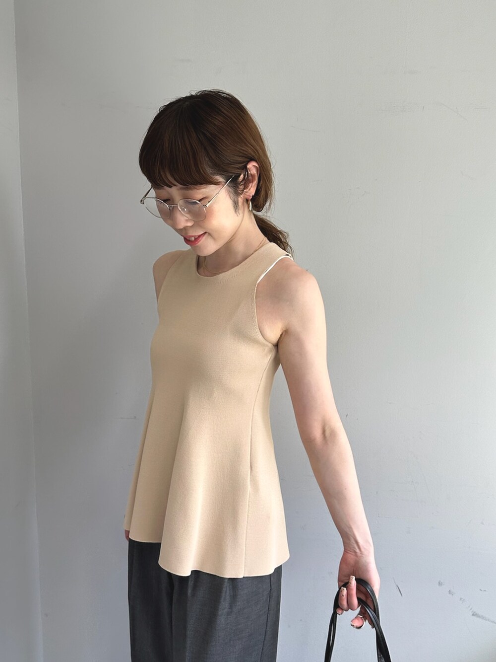 グレー系のスラックス、ホワイト系のハンドバッグ、ブラック系のパンプスを着用したレディースの春コーディネートの7枚目の写真