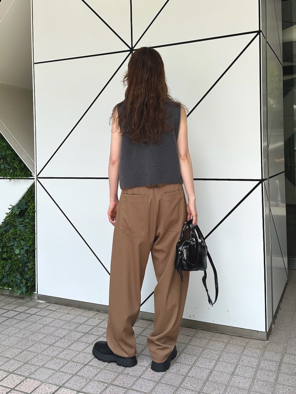 グレー系のベスト、ブラック系のハンドバッグ、ブラック系のブーツを着用したレディースの夏コーディネートの3枚目の写真