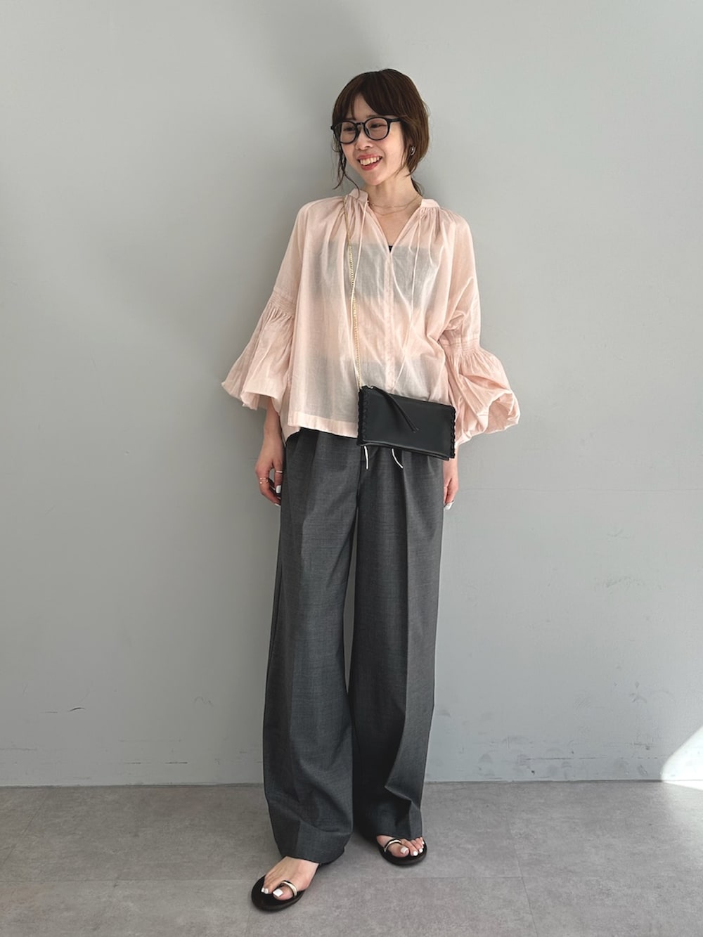 ピンク系のシャツ/ブラウス、グレー系のスラックス、ブラック系のショルダーバッグを着用したレディースの春コーディネートの2枚目の写真