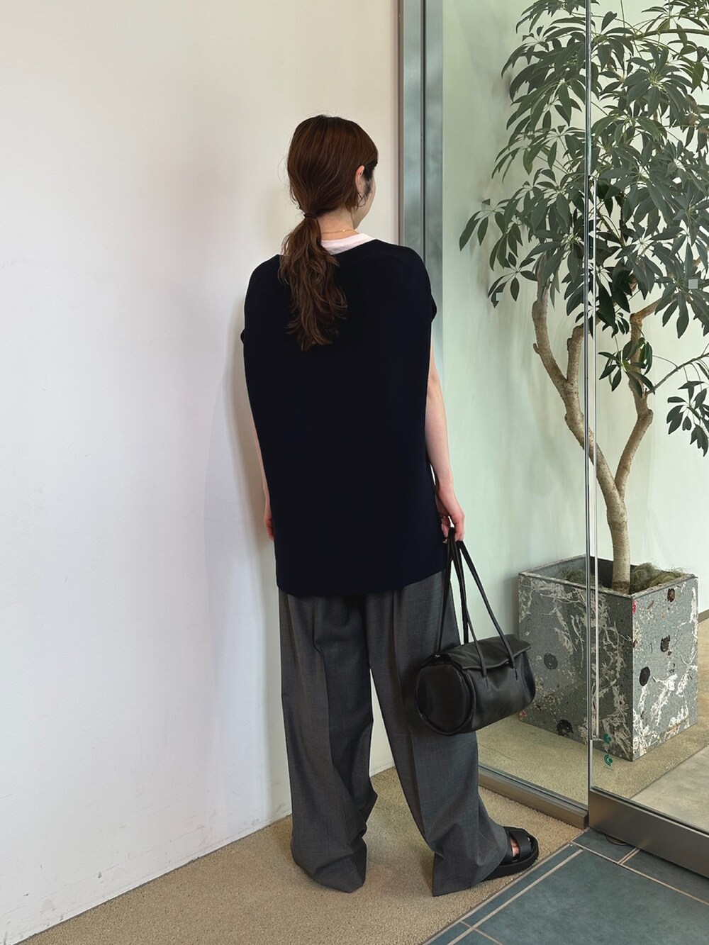 グレー系のスラックス、ホワイト系のハンドバッグ、ブラック系のニット/セーターを着用したレディースの春コーディネートの4枚目の写真