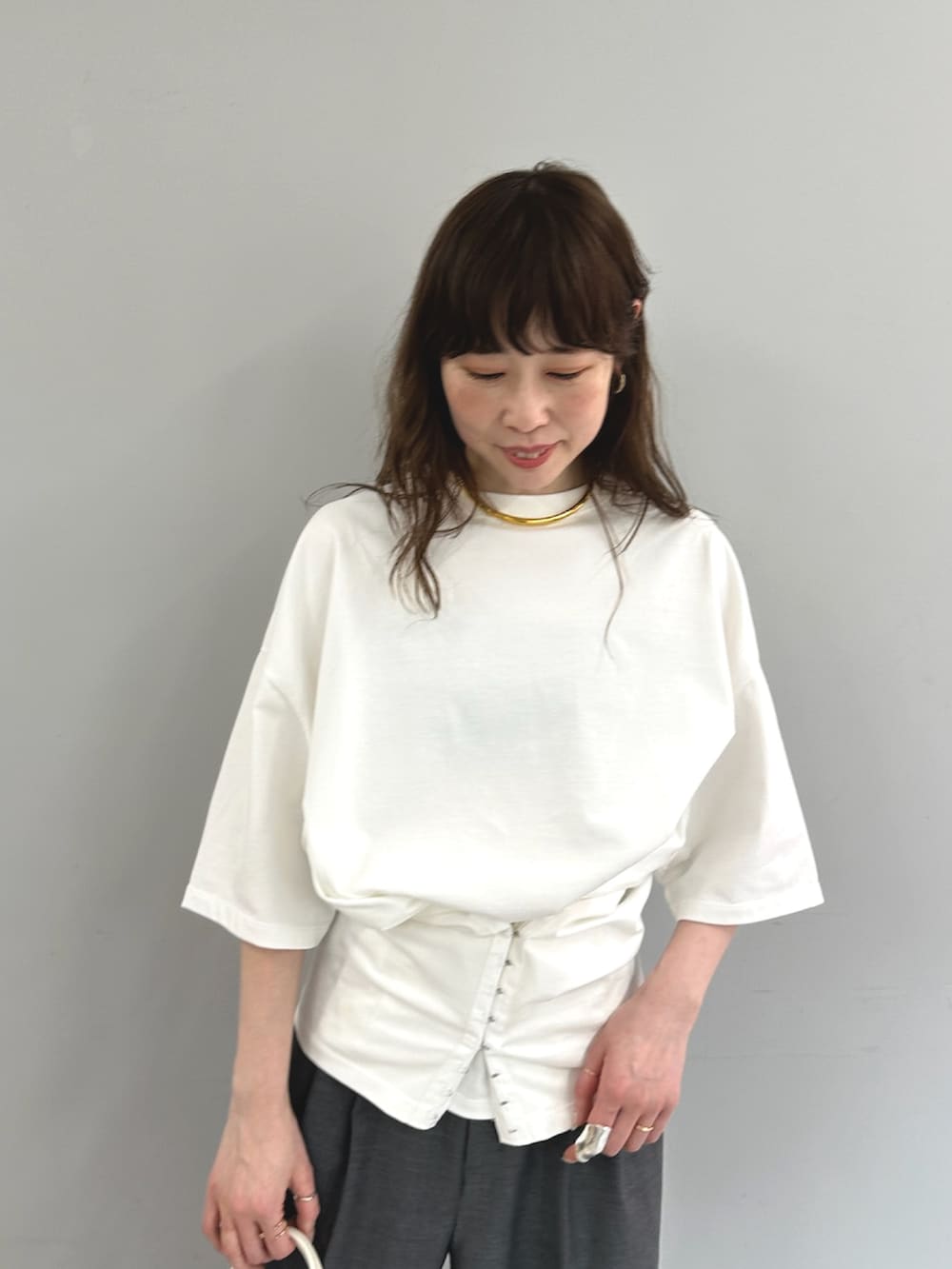 ホワイト系のTシャツ/カットソー、ホワイト系のハンドバッグ、グレー系のスラックスを着用したレディースの春コーディネートの2枚目の写真