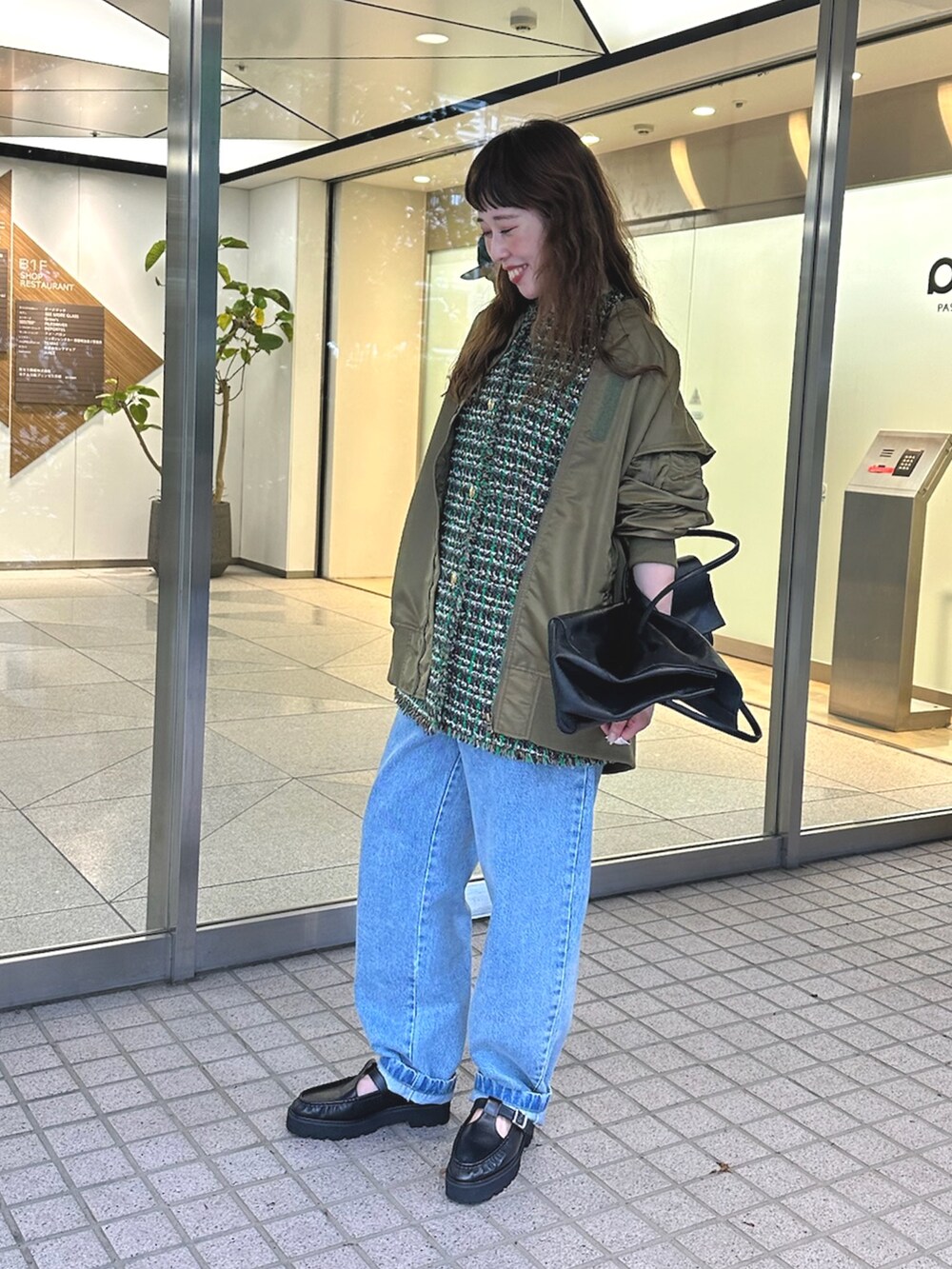 グリーン系のMA-1、ブルー系のデニムパンツ、ブラック系のボストンバッグを着用したレディースの夏コーディネートの2枚目の写真