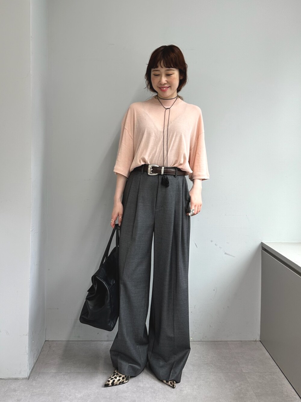 グレー系のスラックス、ブラック系のボストンバッグ、イエロー系のパンプスを着用したレディースの夏コーディネートの2枚目の写真