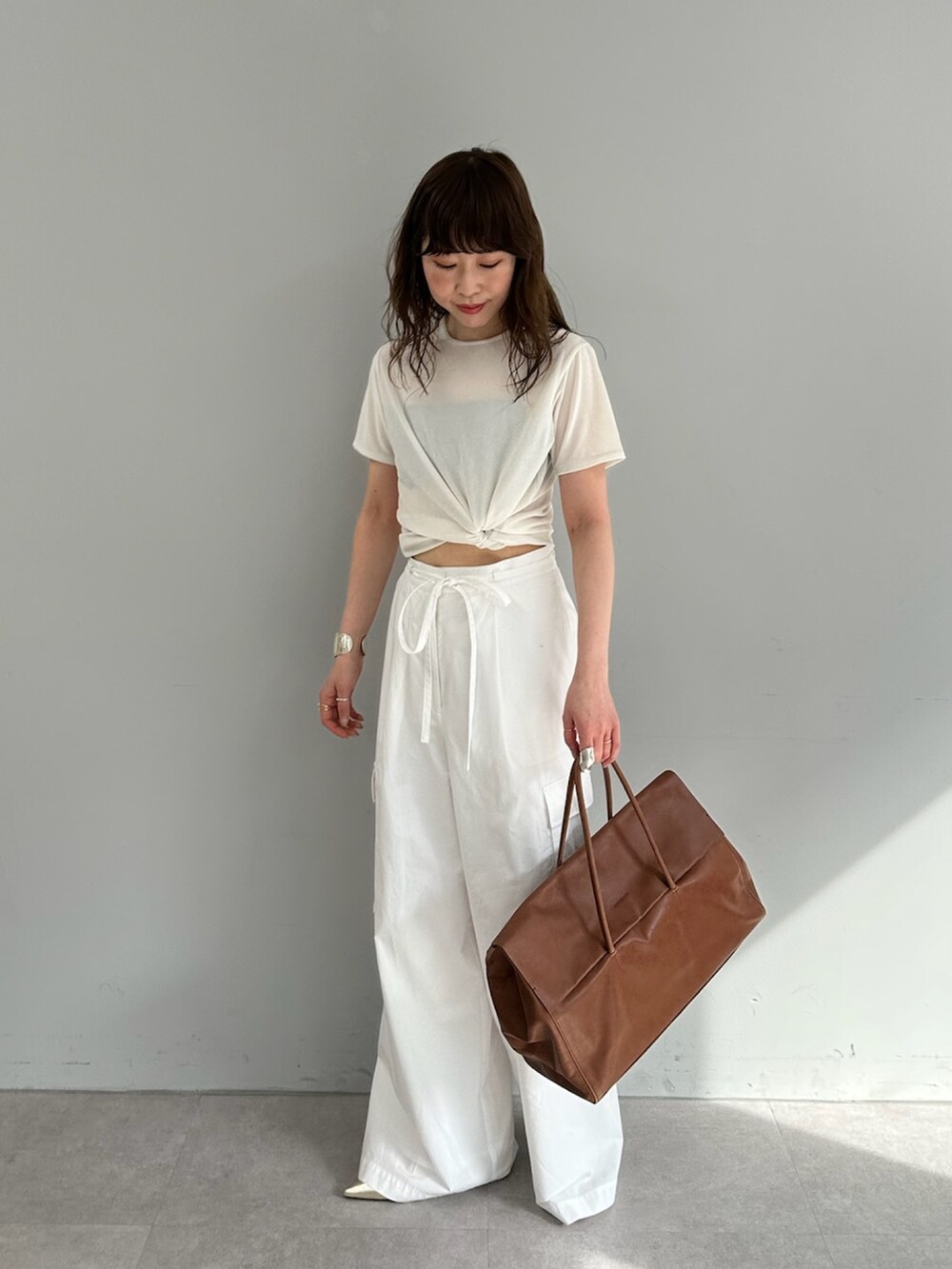 ホワイト系のカーゴパンツ、イエロー系のボストンバッグ、ホワイト系のTシャツ/カットソーを着用したレディースの春コーディネートの3枚目の写真