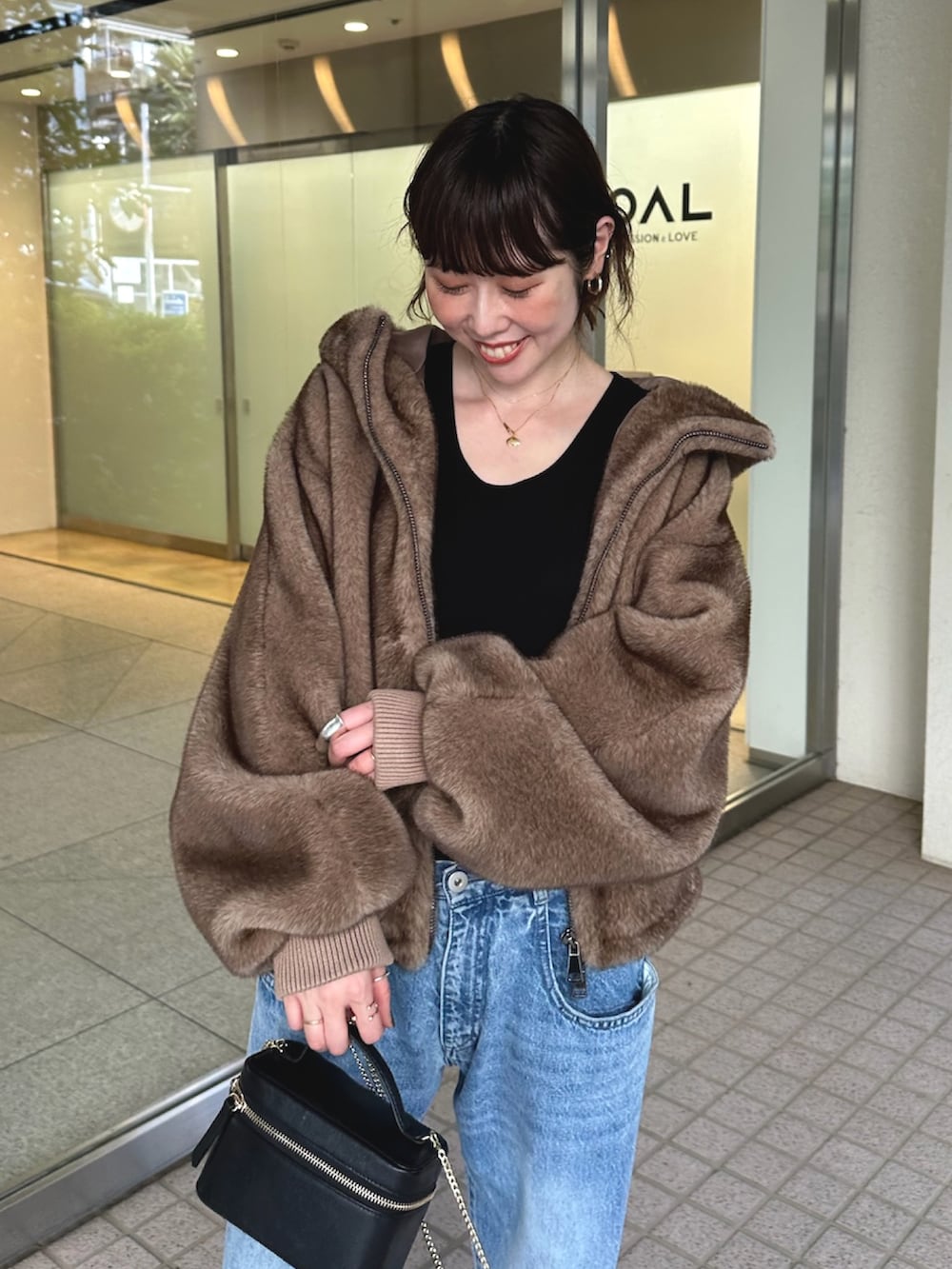 ブルー系のデニムパンツ、ブラック系のショルダーバッグ、ベージュ系のパンプスを着用したレディースの夏コーディネートの5枚目の写真