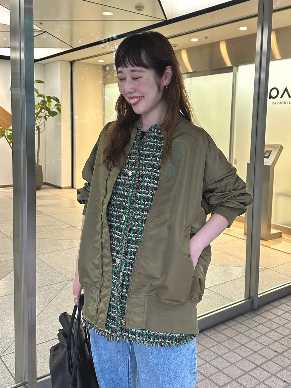 グリーン系のMA-1、ブルー系のデニムパンツ、ブラック系のボストンバッグを着用したレディースの夏コーディネートの4枚目の写真