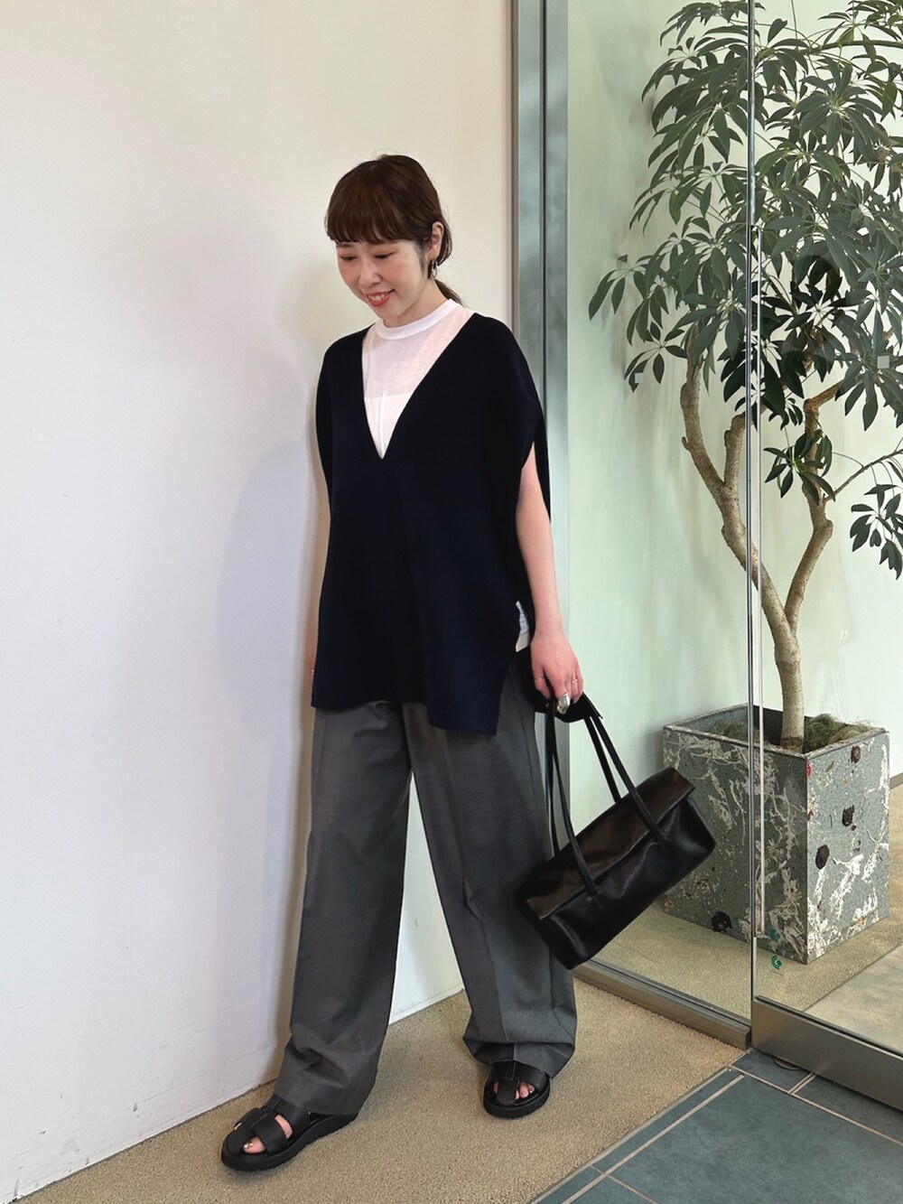 グレー系のスラックス、ホワイト系のハンドバッグ、ブラック系のニット/セーターを着用したレディースの春コーディネートの5枚目の写真