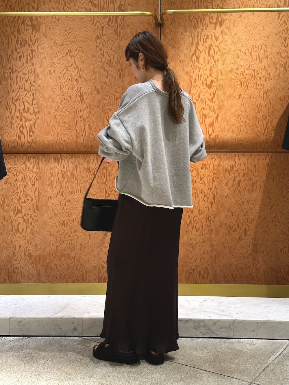 ホワイト系のスウェット、ブラック系のサンダル、ブラウン系のショルダーバッグを着用したレディースの春コーディネートの3枚目の写真