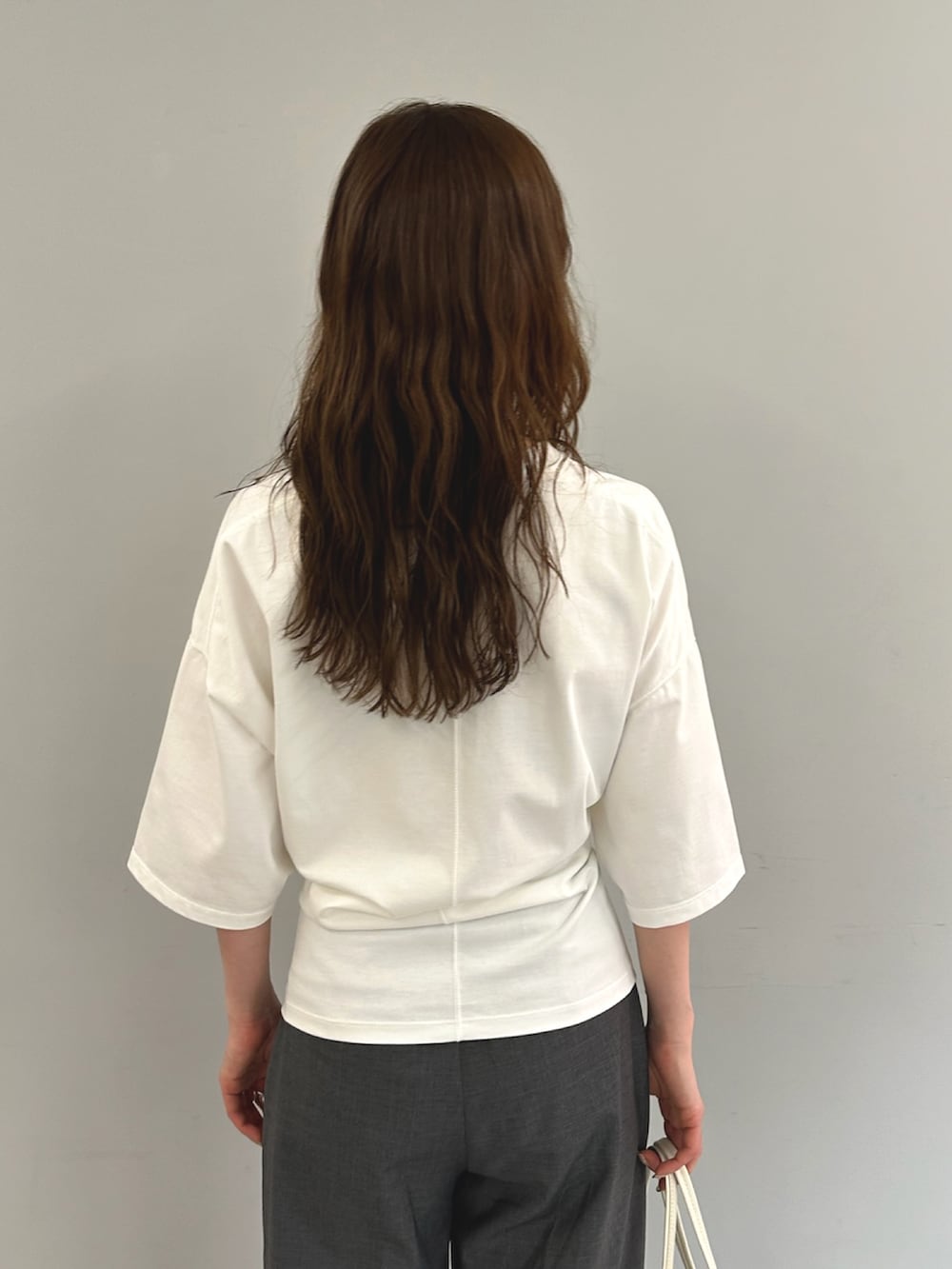 ホワイト系のTシャツ/カットソー、ホワイト系のハンドバッグ、グレー系のスラックスを着用したレディースの春コーディネートの3枚目の写真