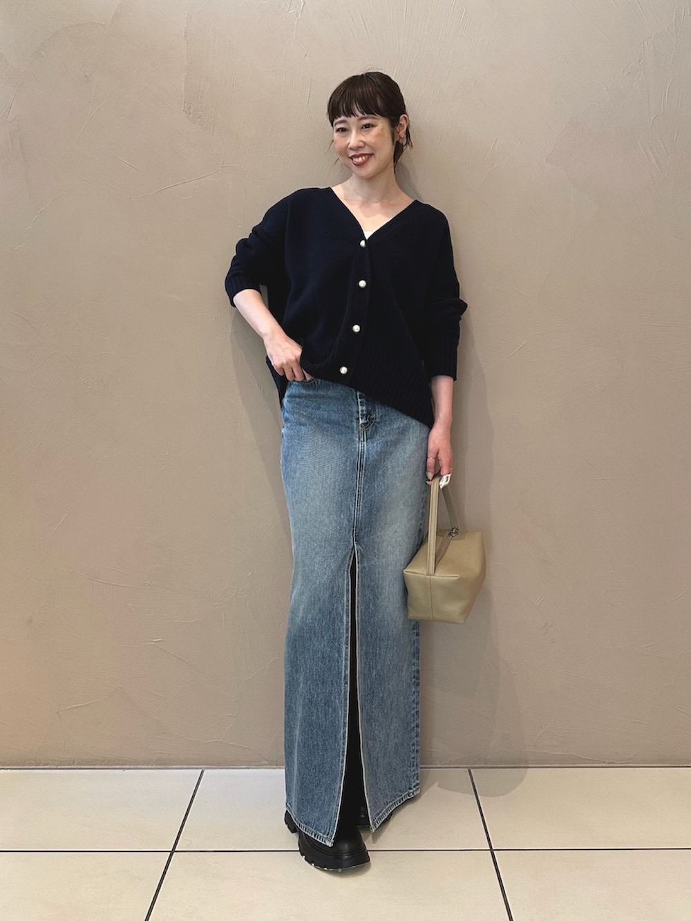 ブルー系のデニムスカート、ブラック系のブーツ、ブラウン系のハンドバッグを着用したレディースの夏コーディネートの5枚目の写真